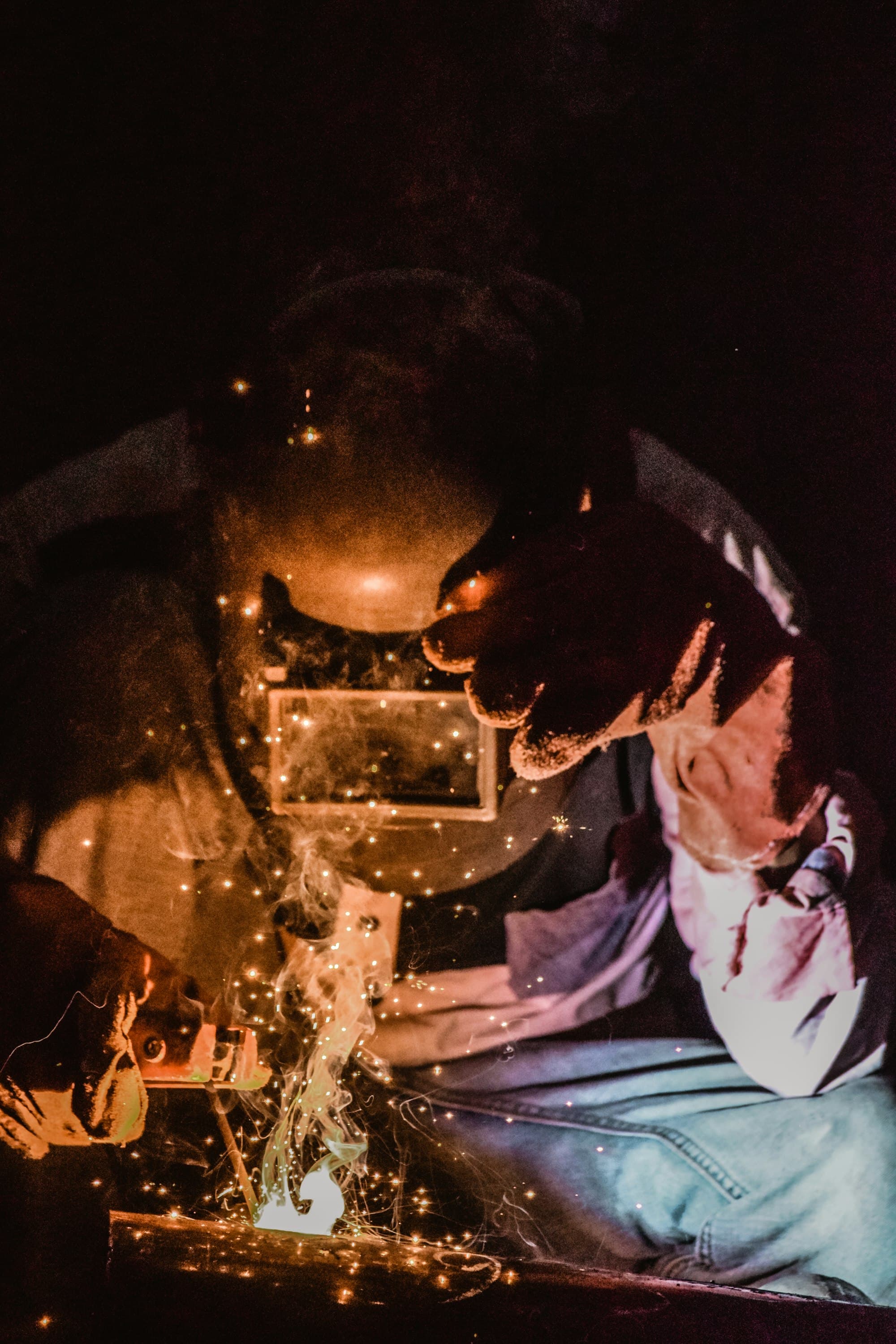 Welder at close range, sparks flying during structural steel fabrication