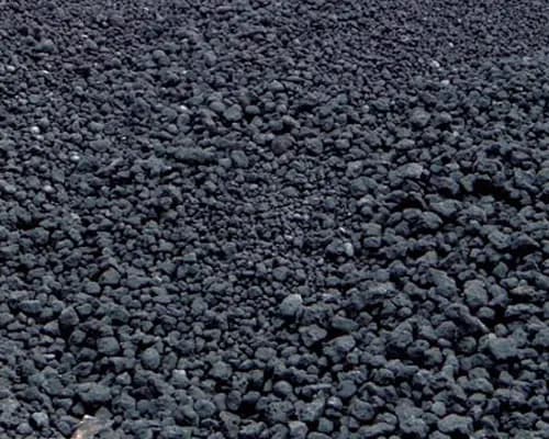 Bulk coke stockpile at an industrial yard, outdoors